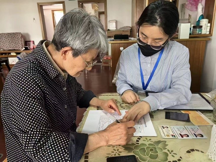 （工作人员指导失能人员家属填写《长期护理失能登记自评表》。单位供图）