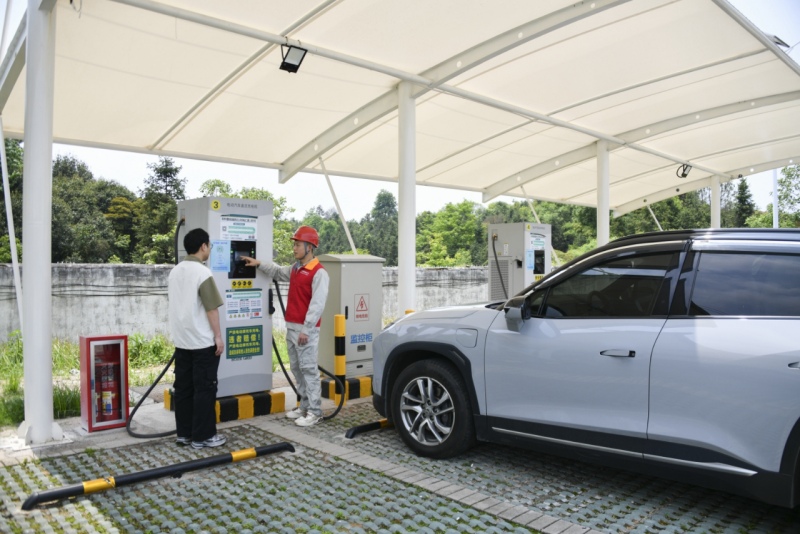 4月30日，國網湖南電動汽車公司東方紅（電動汽車）共產黨員服務隊隊員在朱亭服務區充電站為新能源車主服務。陳靖夫攝