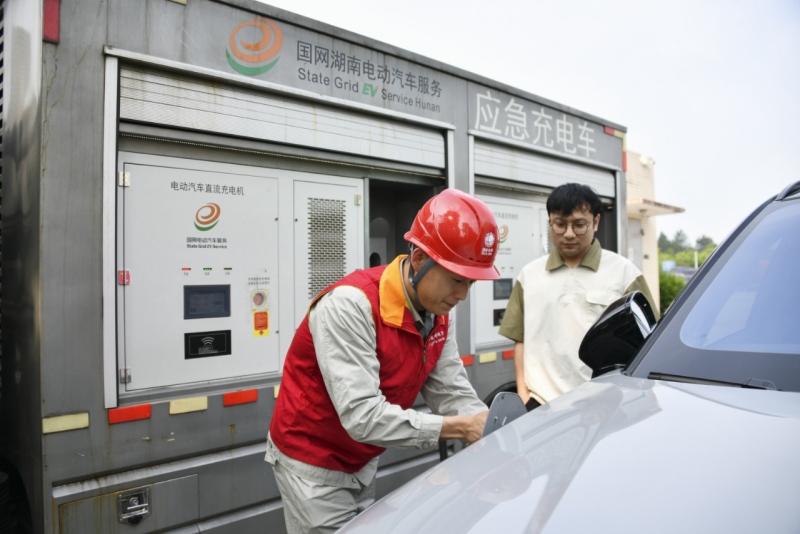 4月30日，國網湖南電動汽車公司東方紅（電動汽車）共產黨員服務隊隊員在朱亭服務區充電站為新能源車主服務。陳靖夫攝