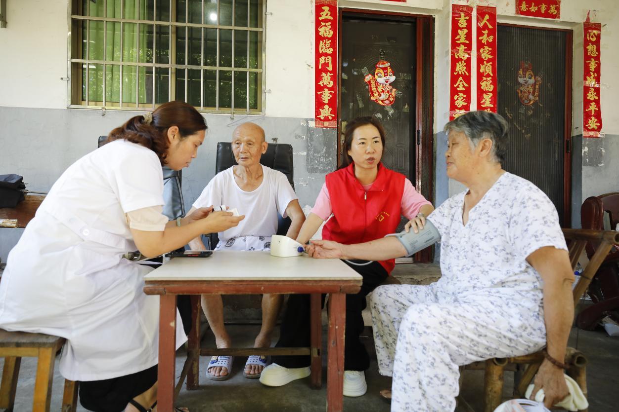 家庭医生王益姒团队为居民测血压，并指导居民用药。唐兰荣摄
