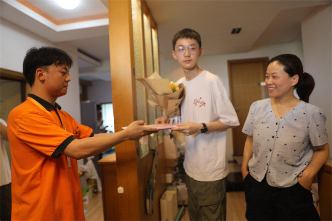 一封来自清华大学的录取通知书送到了考生张乐天（中）的手中。受访单位供图