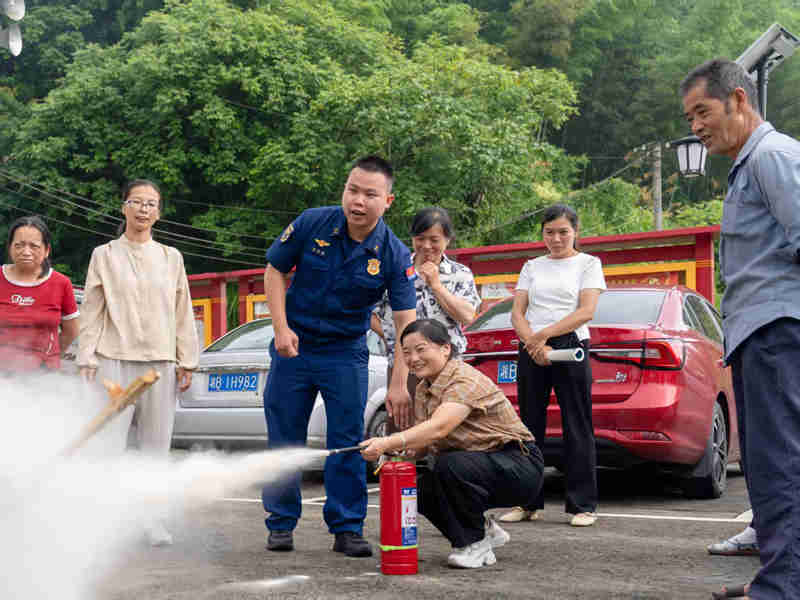 消防宣传员指导如何使用消防器材（单位供图）