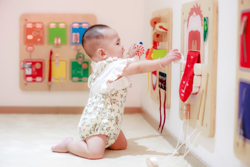 婴儿在玩墙上的玩具。陈艺华摄