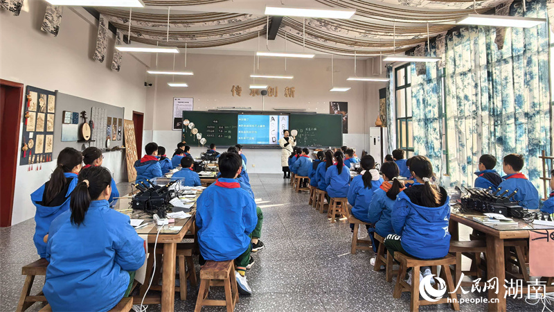 素质教育学校教室内，学生们正烙画团扇制作。人民网记者 吴茜薇摄