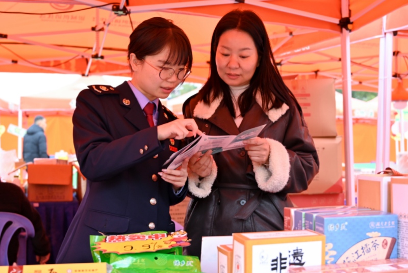 益阳税务干部向年货摊主解读销售非遗产品有关的税收政策。受访单位供图