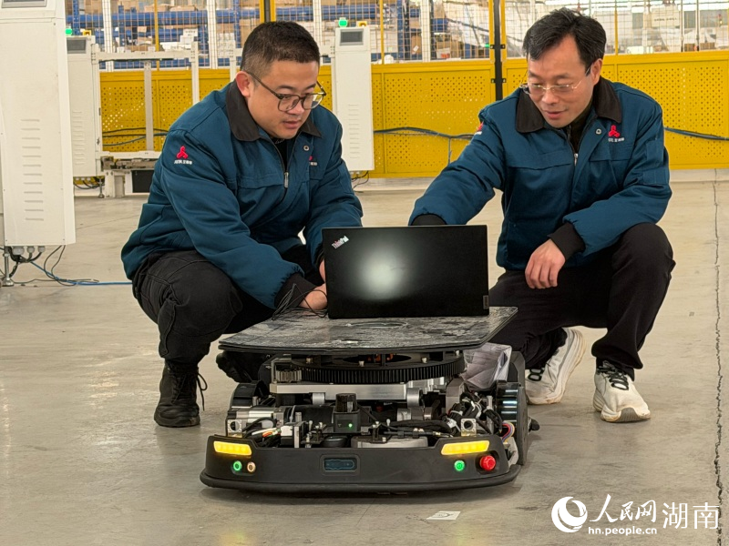 許振東（右一）與技術人員正對自主移動機器人進行數據修改。人民網記者 林洛頫攝