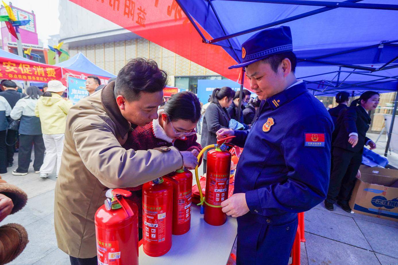 消防宣傳員向往來市民介紹如何辨別消防器材真偽（單位供圖）